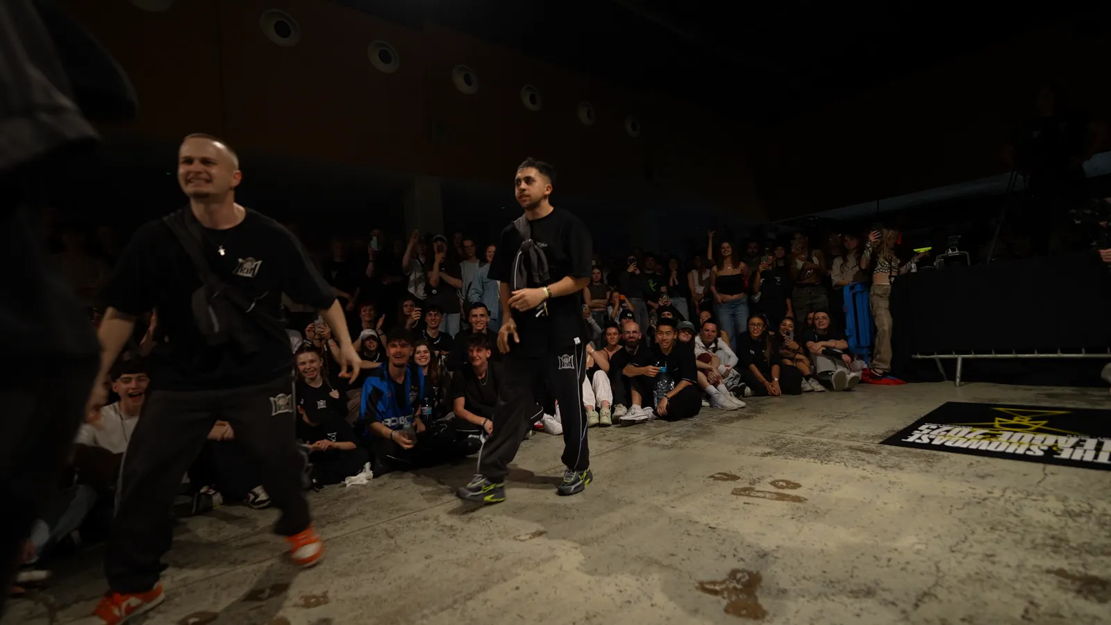 A dancer mid-move, the audience seated around the floor