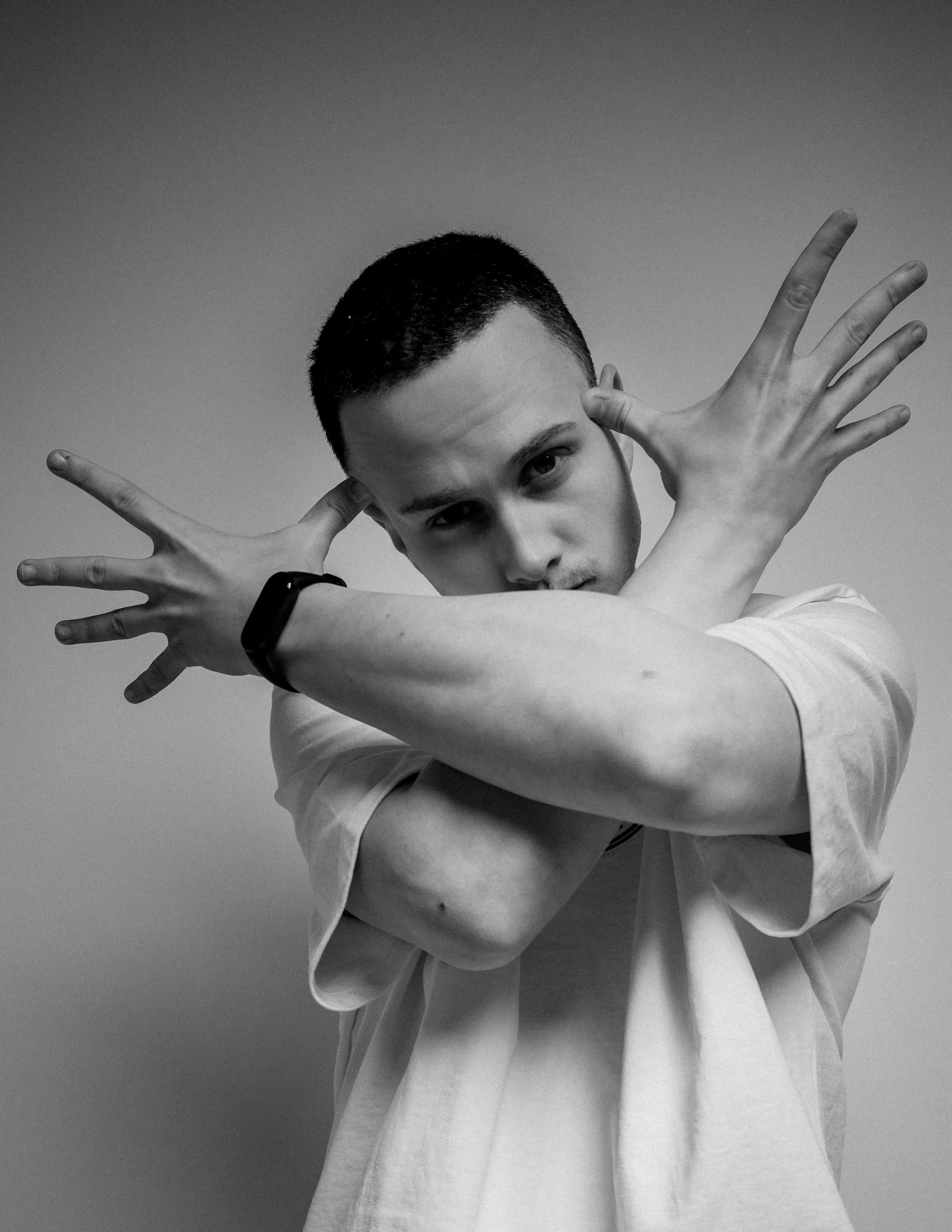 Black and white portrait of Niki, arms crossed in front of his face