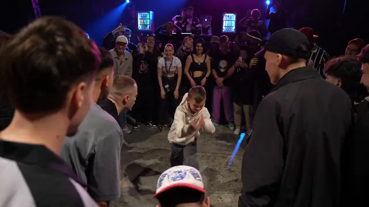 A battle circle with one dancer in the middle under purple lights